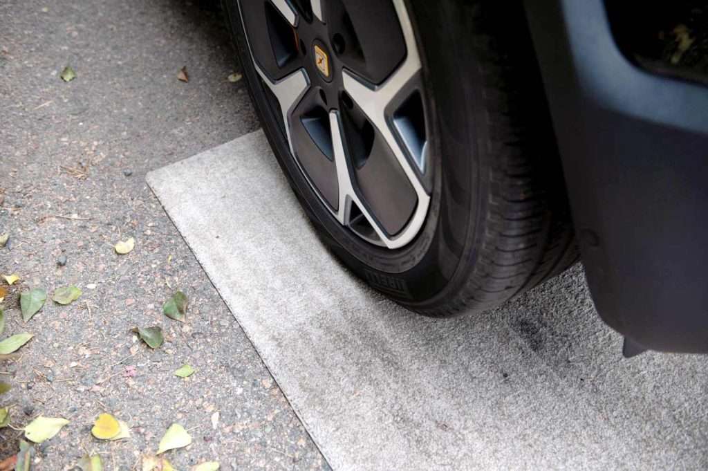 Tire of an SUV driving over a light color floor mat with half protected with stain guard (soil retardant).